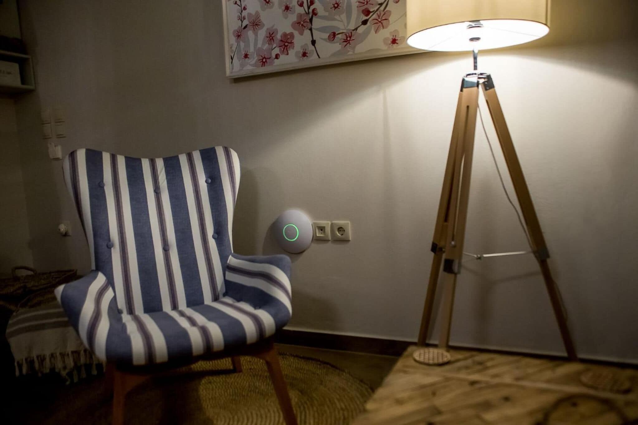 Un sillón a rayas, una lámpara de pie y un enchufe de pared.