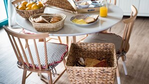 A breakfast table with wicker baskets, plates of food, and a bottle of orange juice.