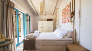 A bedroom with a bed, a wooden nightstand, a chair, a wardrobe, and a large window with curtains.