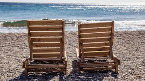 Two wooden beach chairs facing the ocean.