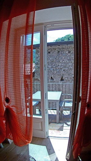 Une pièce dotée d’une porte-fenêtre coulissante donnant sur un patio extérieur avec un mur en pierre, une table et des chaises.