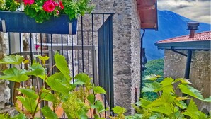 A stone building with a balcony featuring potted plants and flowers.