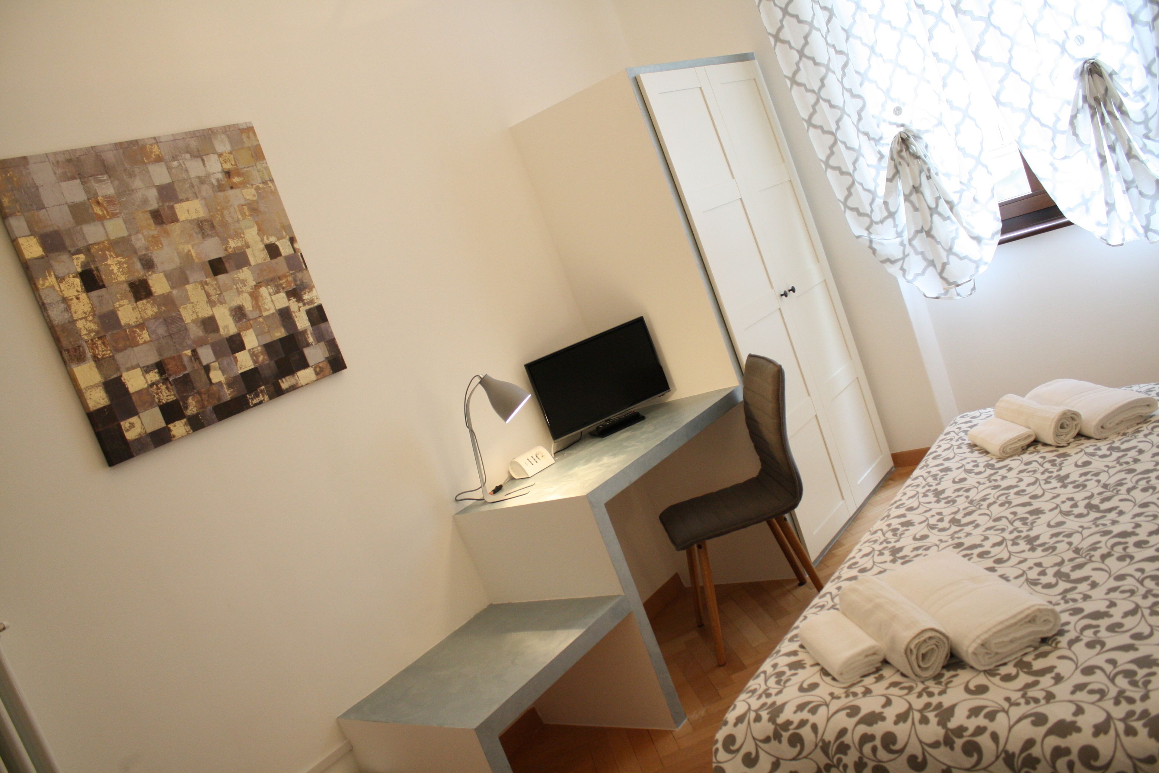Un dormitorio con cama, escritorio con computadora, silla y armario.