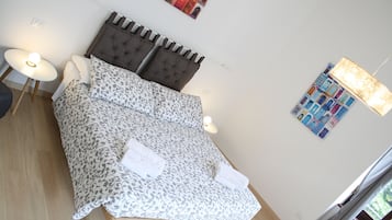 A bedroom with a bed, two bedside lamps, a headboard, and a wall art piece.