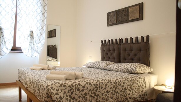 A bedroom with a large bed, a bedside table, a mirror, and a wall-mounted artwork. - Casa Mia - NO Reception (Trento)