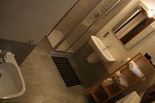 A bathroom with a shower, sink, and a towel rack.