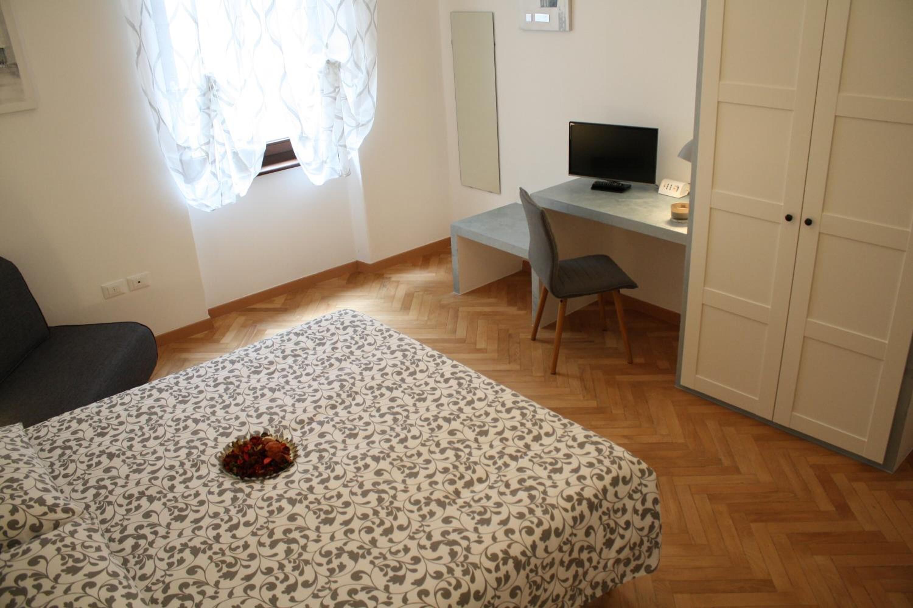 Une chambre à coucher avec un lit, un bureau avec un ordinateur, une chaise et une armoire.