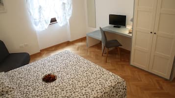 Un dormitorio con una cama, un escritorio con una computadora, una silla y un armario.