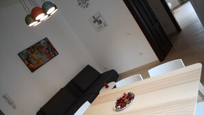 A modern dining area with a wooden table, white chairs, a black sofa, and a decorative plate of flowers. - Casa Mia - NO Reception (Trento)