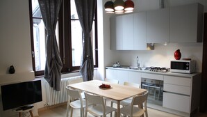 A modern kitchen with white cabinets, a wooden dining table, and a TV. - Casa Mia - NO Reception (Trento)