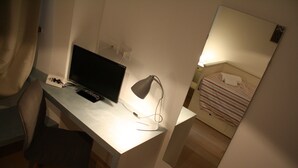 A hotel room with a desk, a computer, a lamp, a bed with a striped blanket, and a mirror on the wall. - Casa Mia - NO Reception (Trento)
