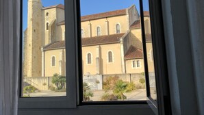 A window view of a building with a tower and a courtyard. - Le Bon Geours (Saint-Geours-de-Maremne)