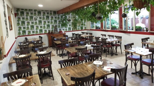 A restaurant with wooden tables and chairs, a counter, and hanging plants. - Le Bon Geours (Saint-Geours-de-Maremne)