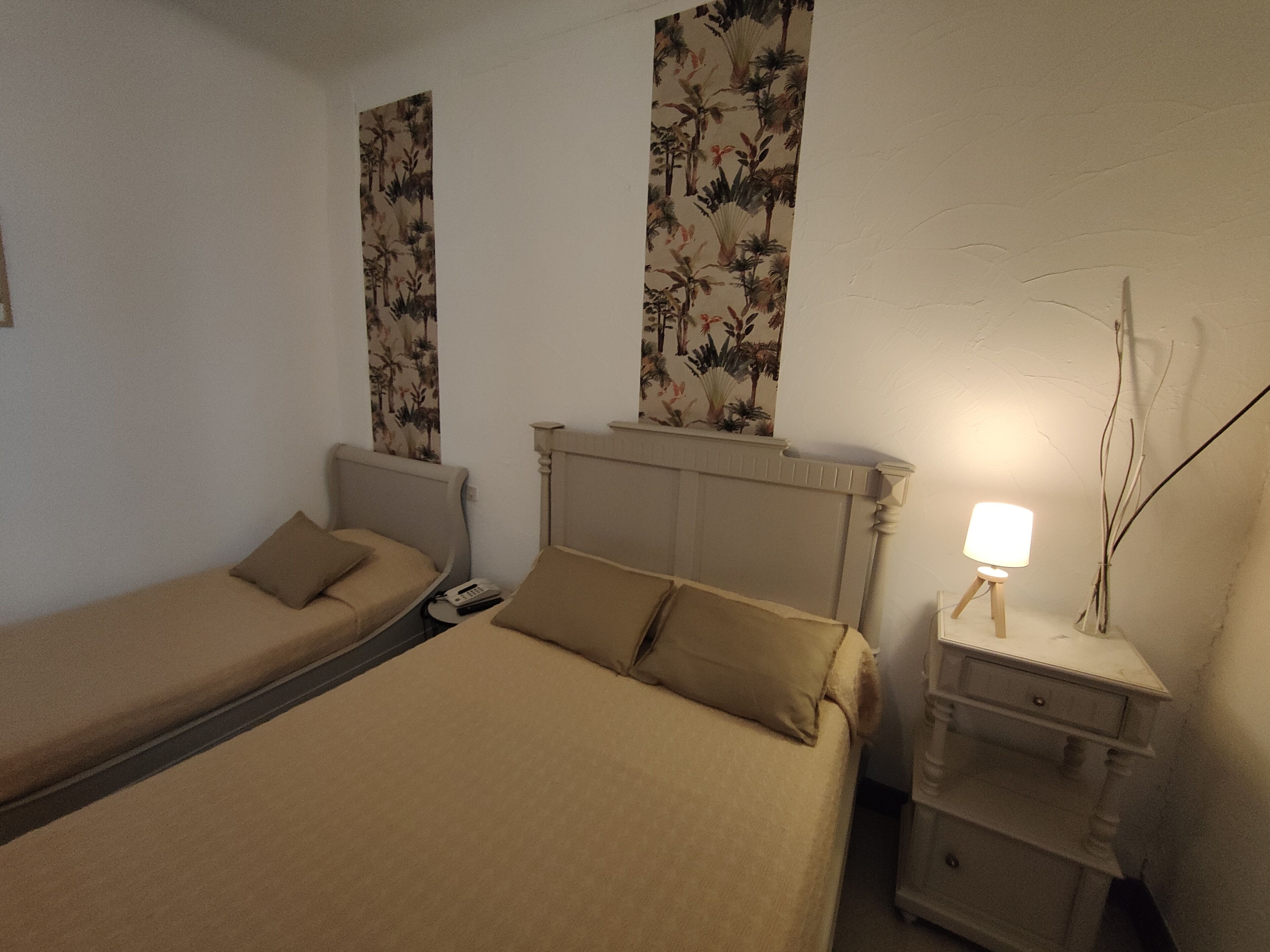 Un dormitorio con dos camas individuales, una mesita de noche con lámpara y un tocador con teléfono.