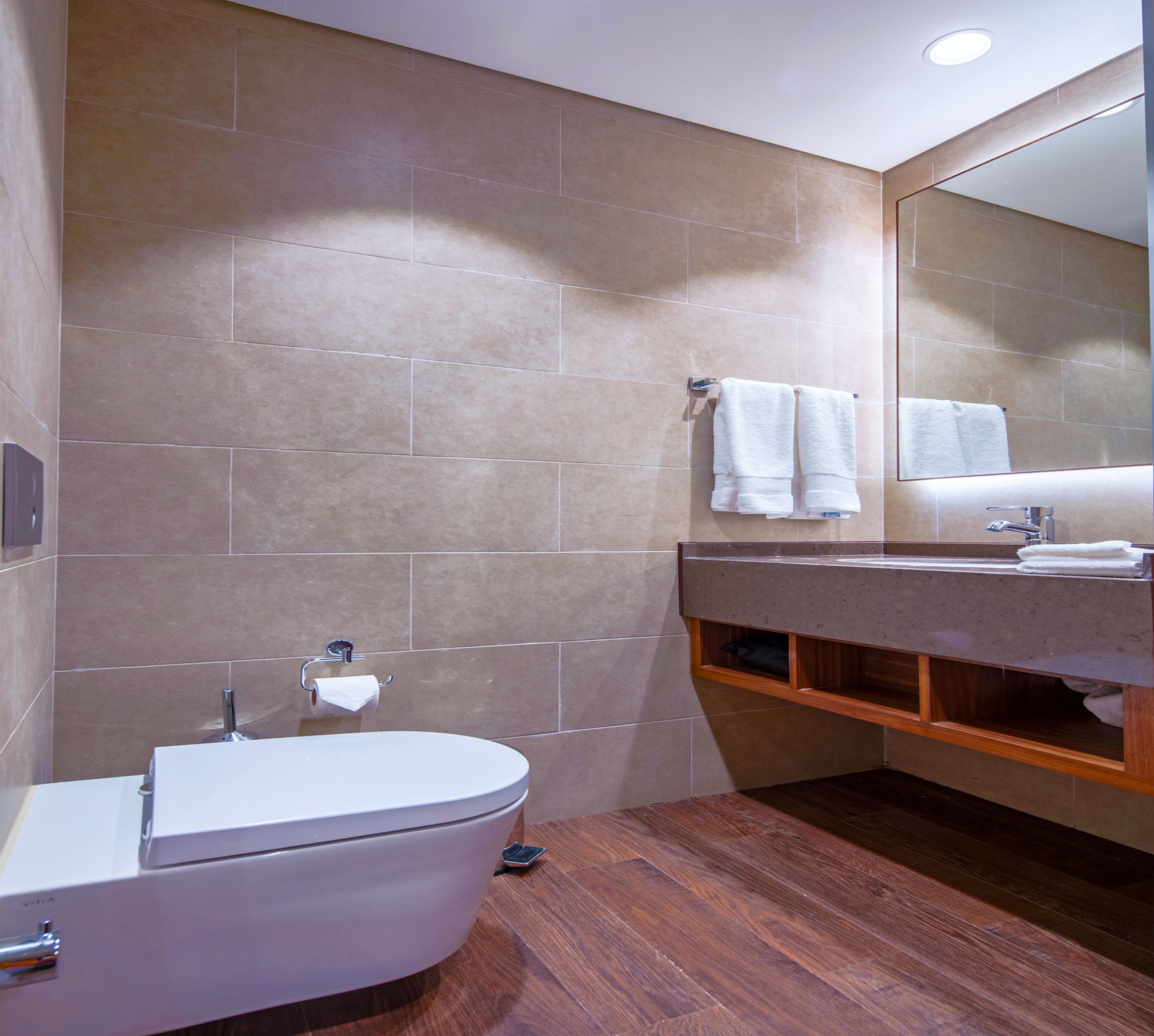Ein modernes Badezimmer mit Toilette, Waschbecken und Spiegel.
