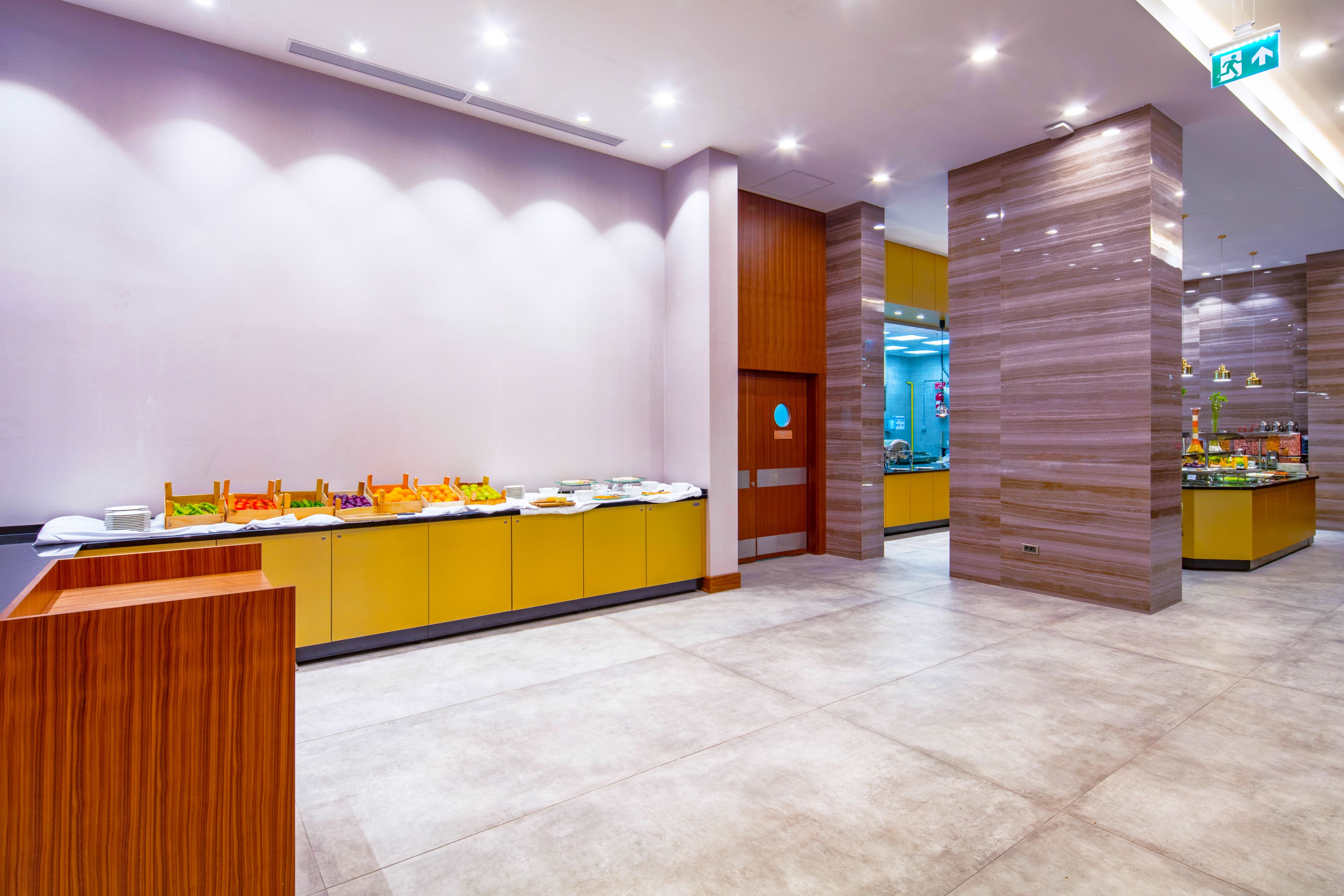 A modern reception area with a counter, a buffet with various food items, and a wooden accent wall.