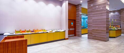 A modern reception area with a counter, a buffet with various food items, and a wooden accent wall.