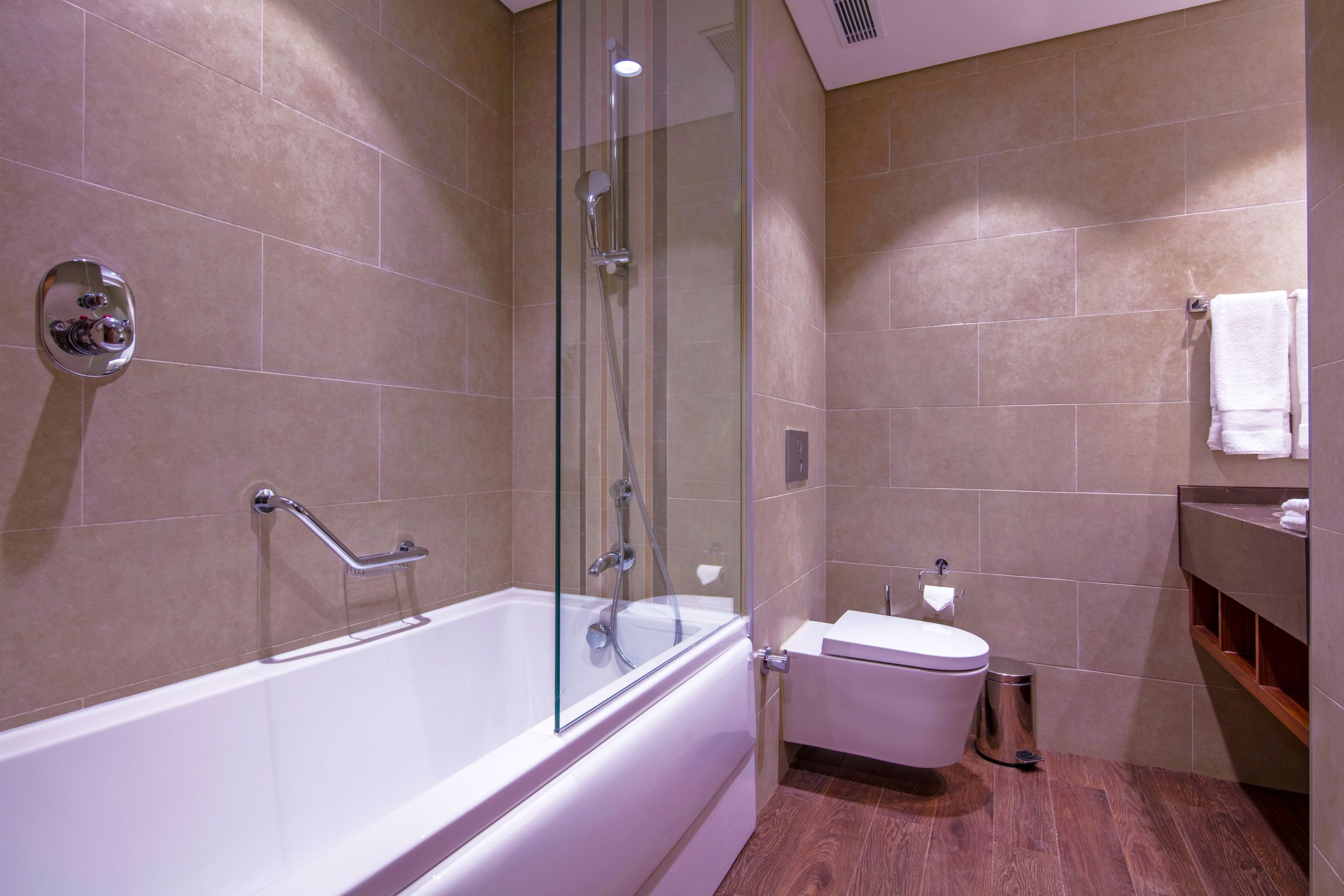 Ein modernes Badezimmer mit einer gläsernen Duschkabine, einer weißen Badewanne und Holzboden.