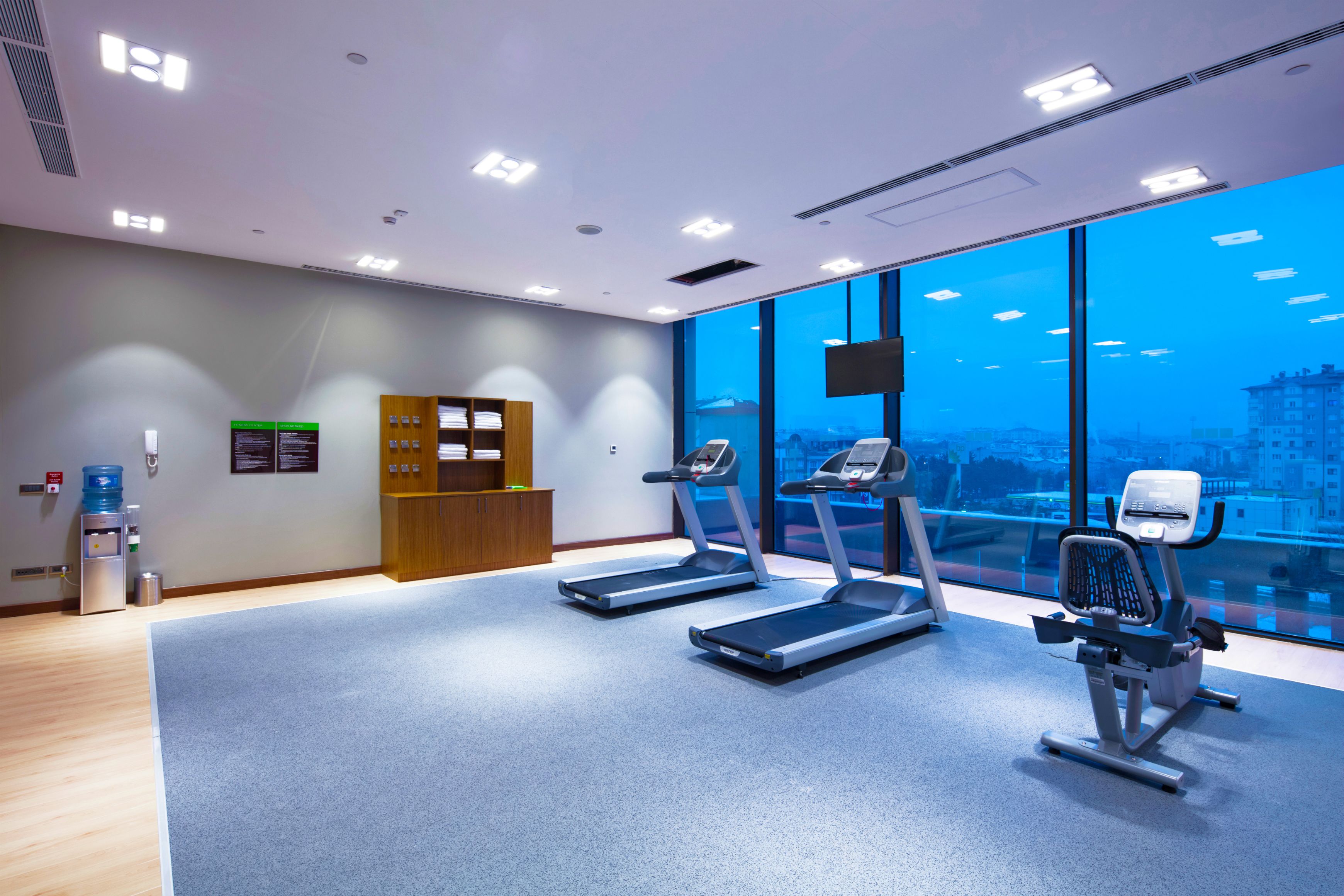 A modern fitness room with treadmills, a stationary bike, and a water dispenser.