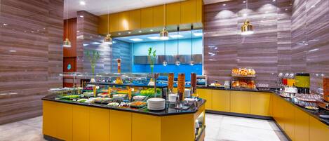 Un espace buffet doté d’un îlot central, de plusieurs luminaires suspendus et d’un design moderne aux tons jaunes et bruns.