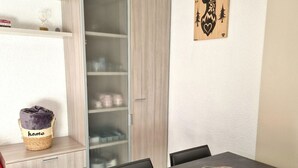 A modern dining area with a dark table, a woven basket with a blanket, and a decorative wall piece. - Cozy 4-6 Person Apartment in Ski Resort Center with Balcony and Modern Amenities (Valfréjus)