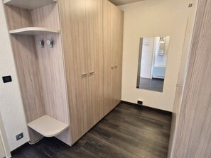 Ein kleiner, abgeschlossener Raum mit einem Holzschrank, einem Spiegel und einem kleinen Regal.
