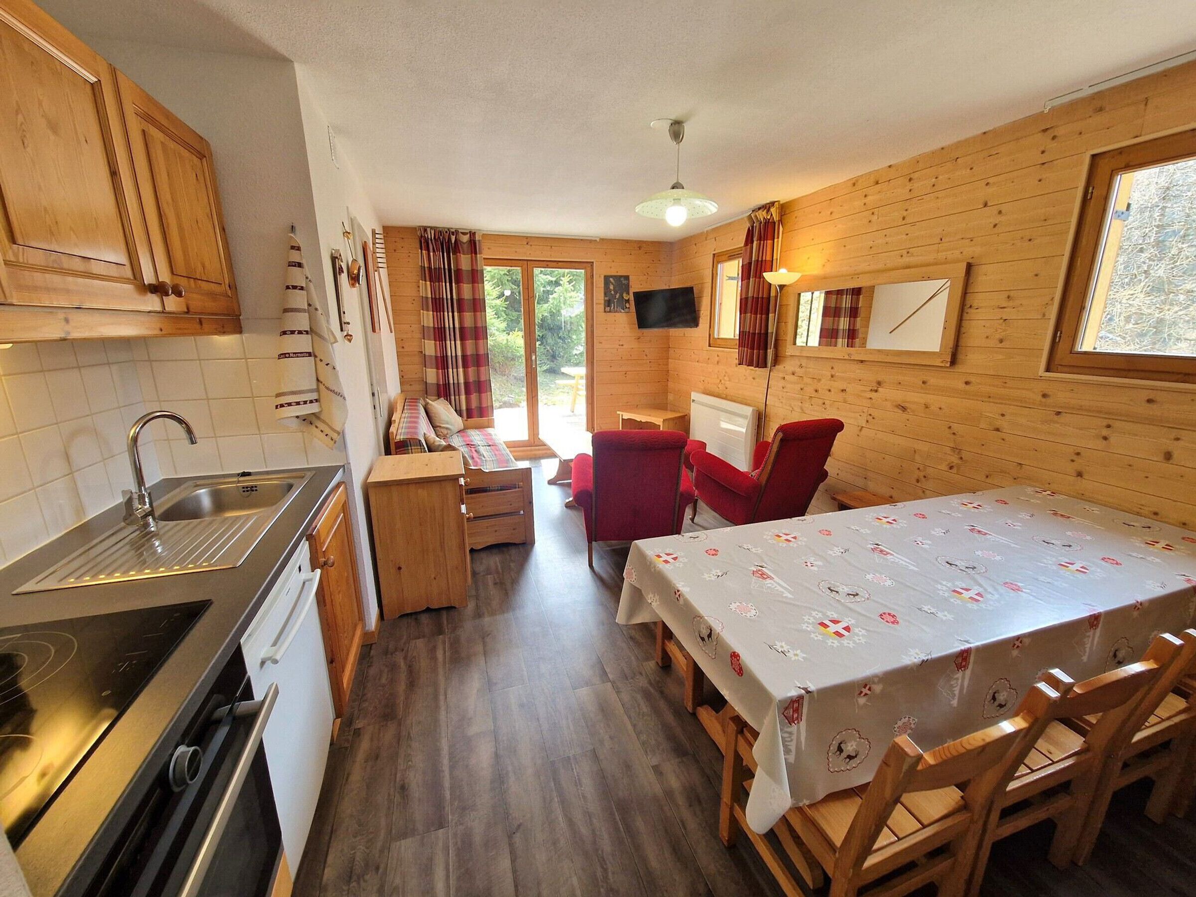 Une cuisine compacte avec des meubles de rangement en bois, un évier et un coin repas comprenant une table et des chaises.