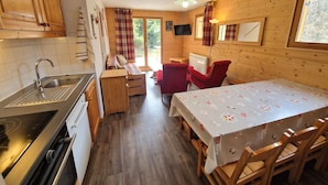 A compact kitchen with wooden cabinets, a sink, and a dining area with a table and chairs.