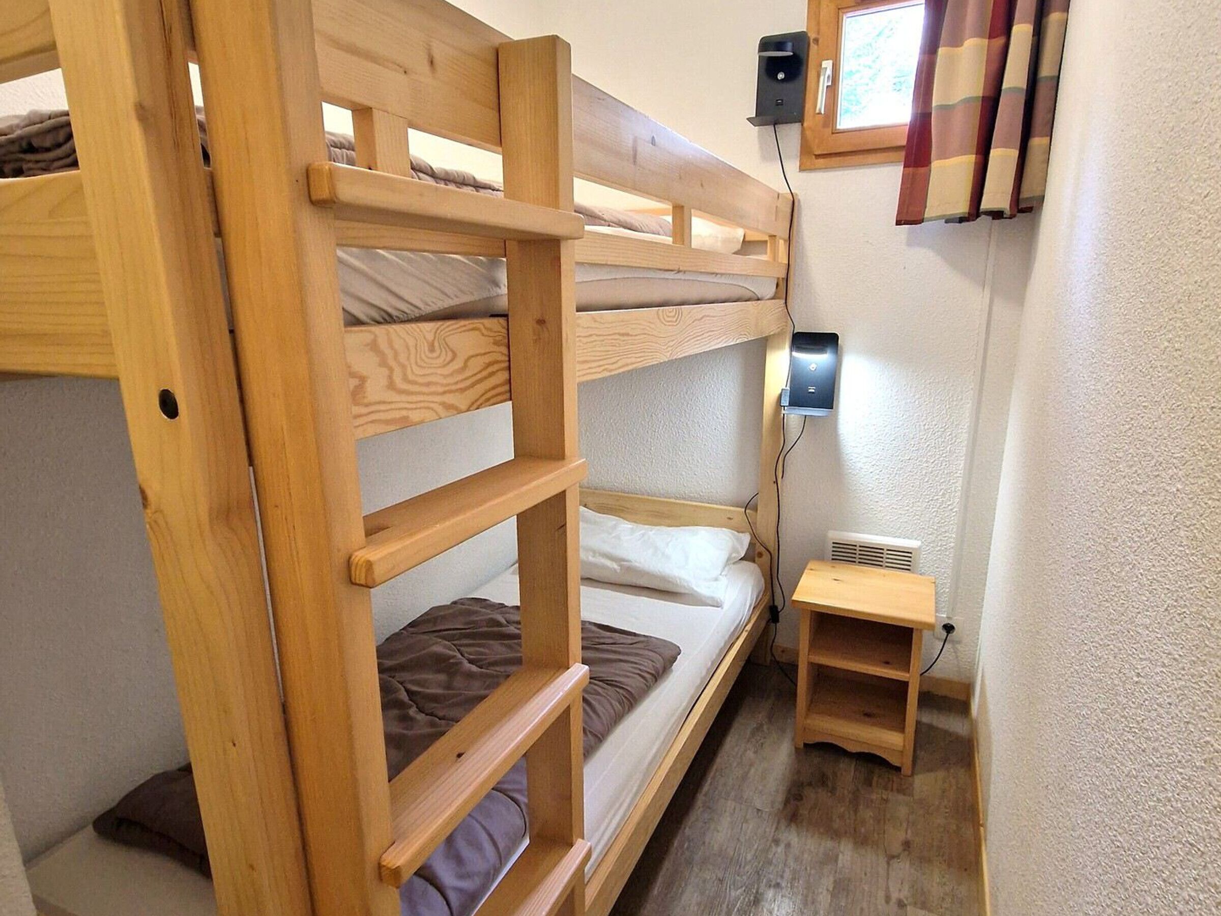 A bunk bed room with a small wooden table and a heater.