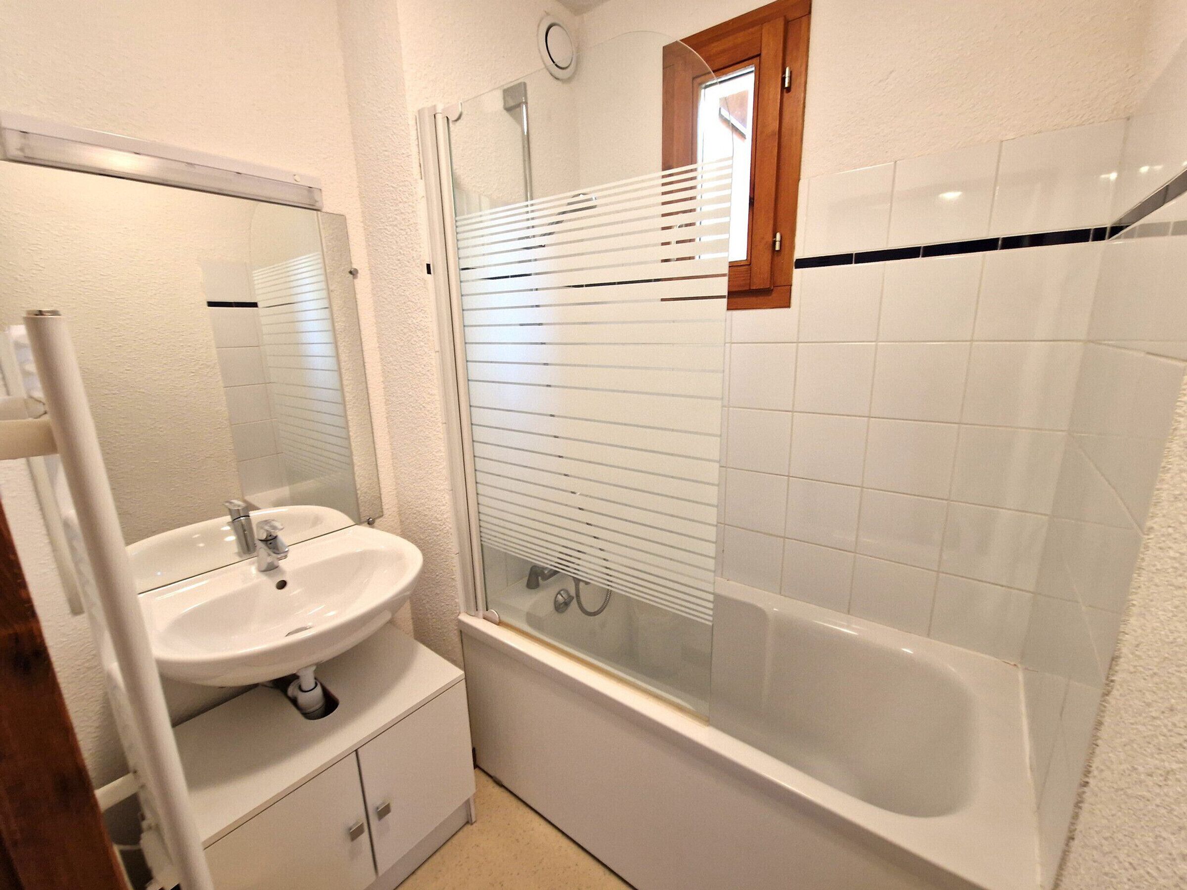 A bathroom with a white sink, mirror, and bathtub.