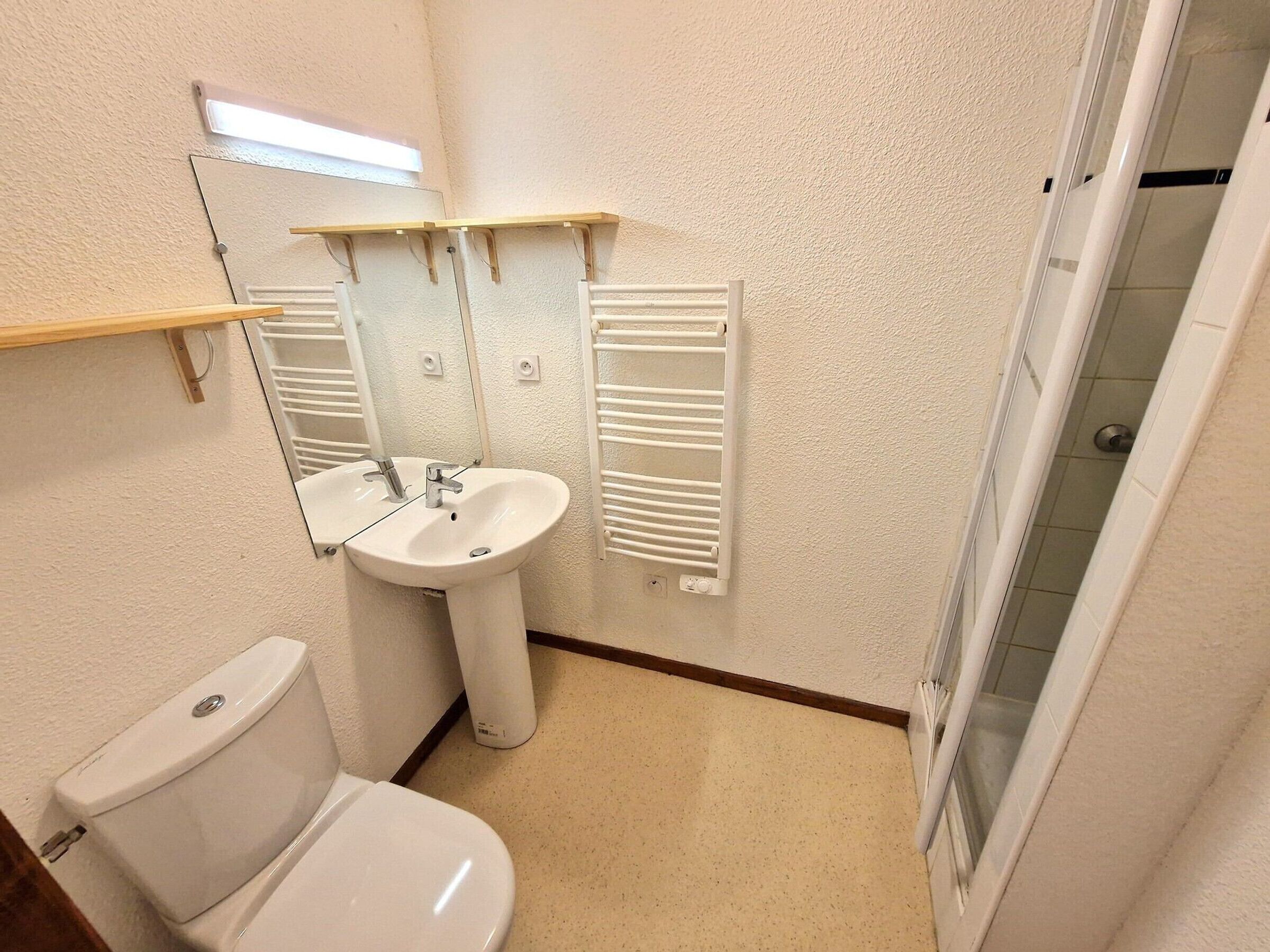 A small bathroom with a toilet, sink, and a mirror.