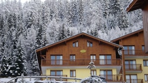 Una cabaña de madera con balcones, rodeada de árboles cubiertos de nieve.