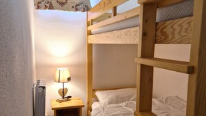 Ein Schlafraum mit Etagenbetten, einem Holzkopfteil, einem Nachttisch mit Lampe und einer Heizung.