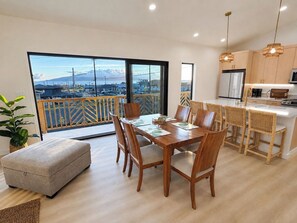 Eine moderne Küche mit Holzausstattung, ein Essbereich mit Tisch und Stühlen sowie ein Balkon mit Bergblick.