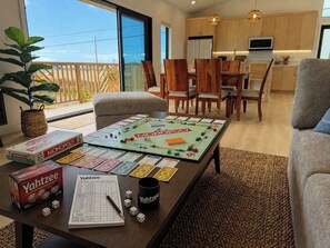 A living room with a Monopoly board game, Yahtzee, and dice on a coffee table. - Brand-new Maui home with comfort and local charm! (Lahaina)