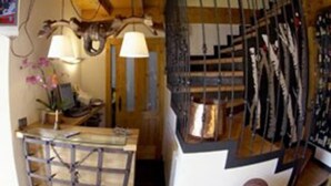 Een rustiek interieur met houten balken, een metalen rek en een hanglamp.