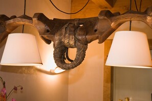 Une sculpture en bois représentant la tête d’un éléphant, à laquelle sont suspendues deux lampes.