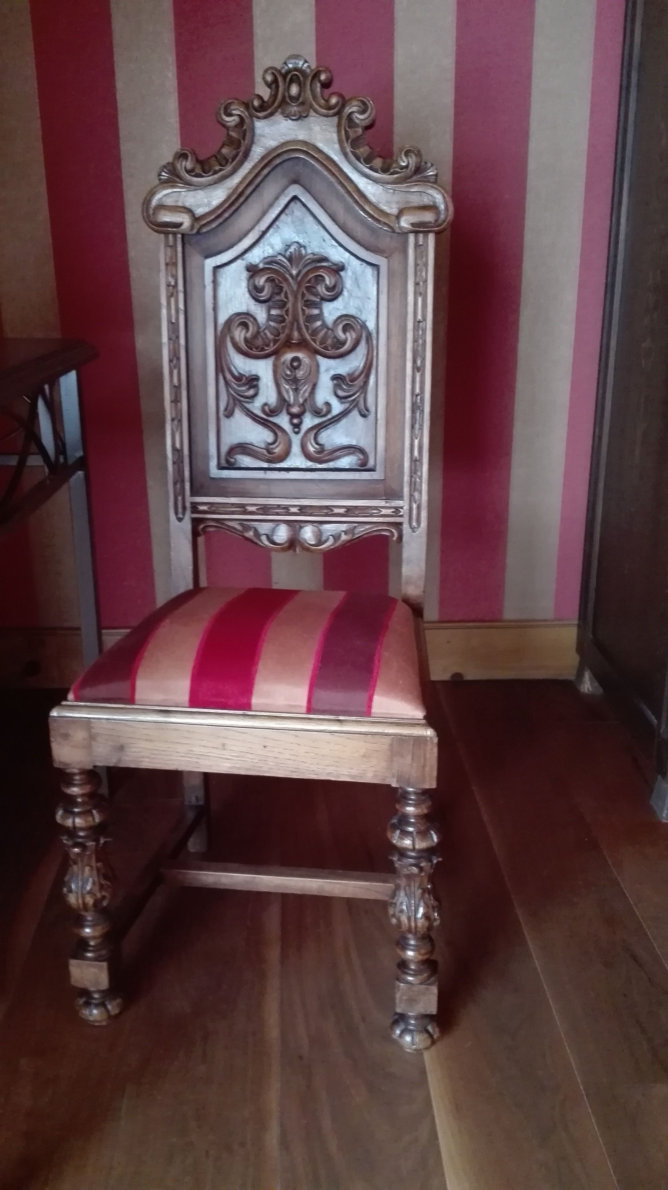 Une chaise en bois avec un coussin à rayures et un dossier décoratif, placée contre un mur à rayures.