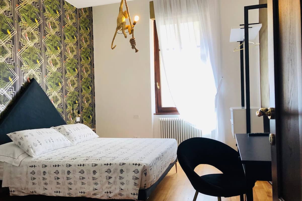 A bedroom with a bed, a desk, and a chair.
