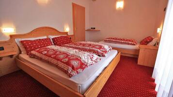 Un dormitorio con una cama de madera, dos mesitas de noche, una alfombra roja y luces fijadas en la pared.