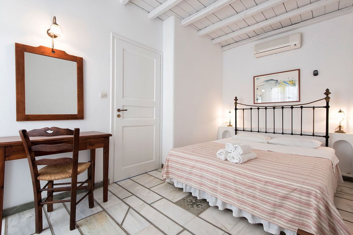 A bedroom with a bed, a desk, a chair, and a door.