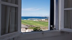 A view from a window overlooking a coastal landscape with buildings and greenery. - Brachera Apartments (Paros)