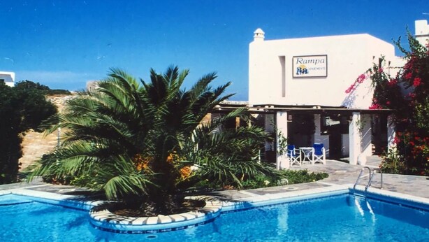 A swimming pool with a palm tree and a building labeled "Kampa Hotels". - Brachera Apartments (Paros)