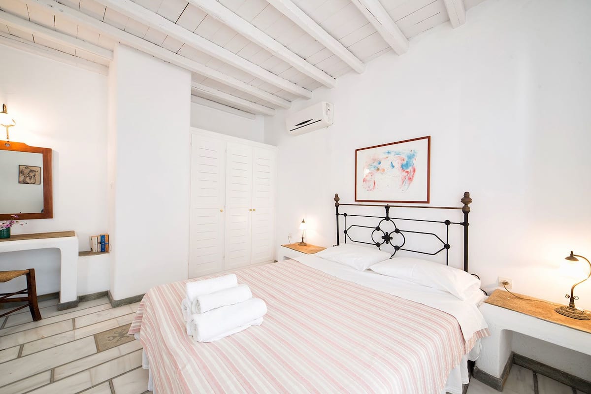 A bedroom with a bed, bedside tables, a desk, and a wardrobe.