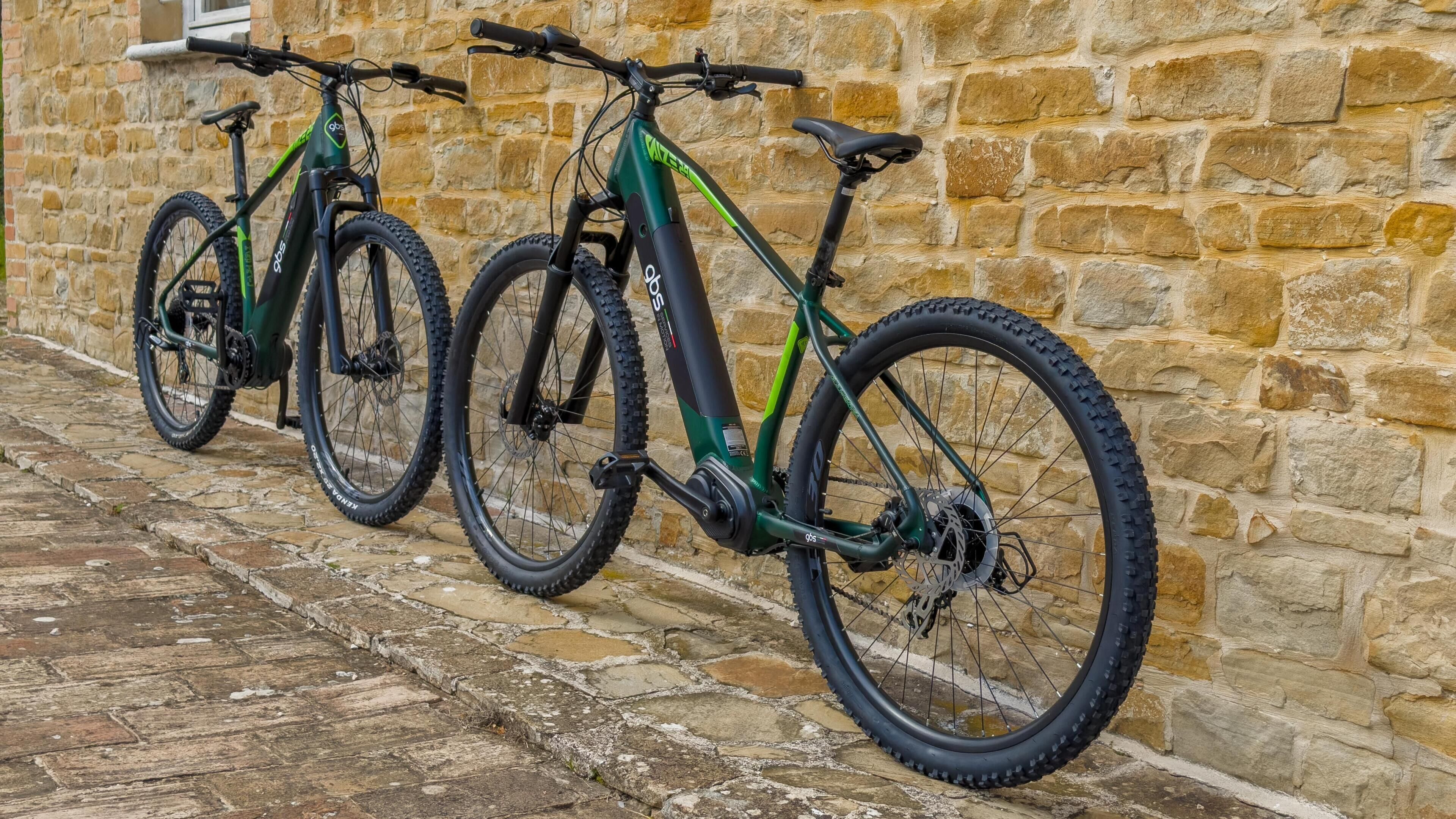 Two bicycles parked against a stone wall.