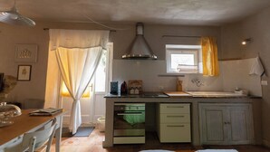 Une cuisine équipée d’une cuisinière, d’un four, d’un évier et d’une fenêtre avec des rideaux.