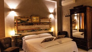 Une chambre d’hôtel avec un grand lit, deux tables de chevet, une chaise, un miroir et une œuvre d’art accrochée au mur.