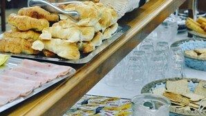 A buffet table with various food items including pastries, fruits, and sandwiches.