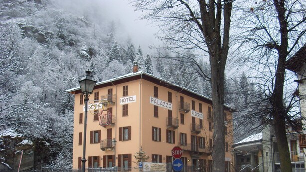 Et hotel med flere balkoner og et skilt, der angiver et stoppested forude.