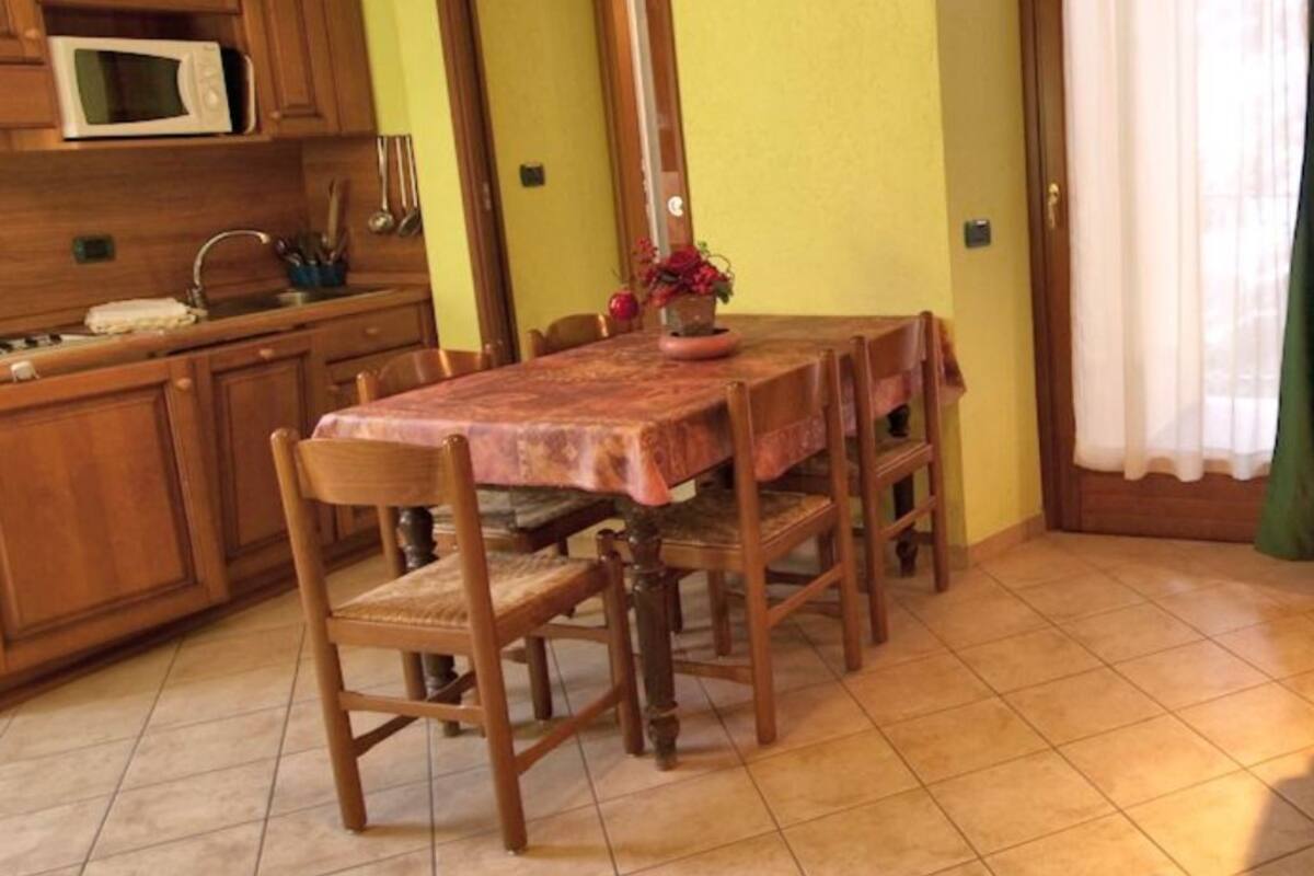 Ein gemütliches Wohnzimmer mit einer Couch und einem Esstisch mit Stühlen. Im Küchenbereich steht eine Mikrowelle.